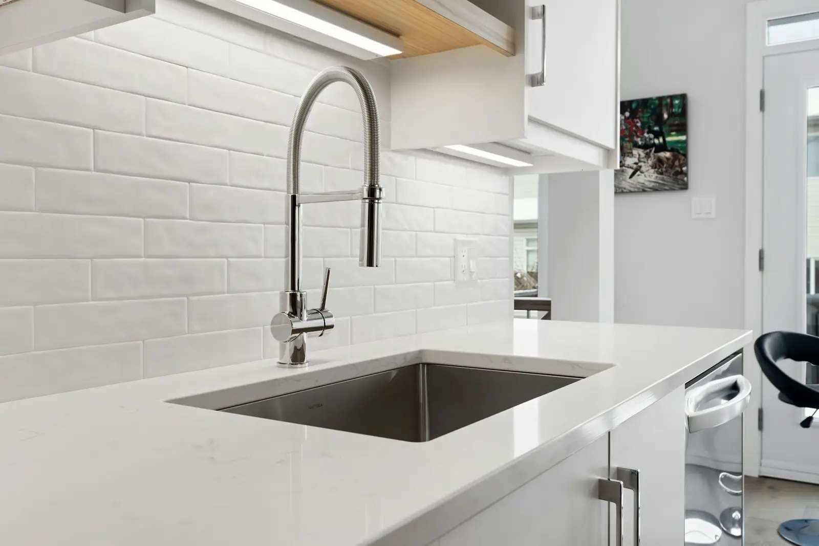Kitchen sink with a pull-out spray tap beneath white wall tiles