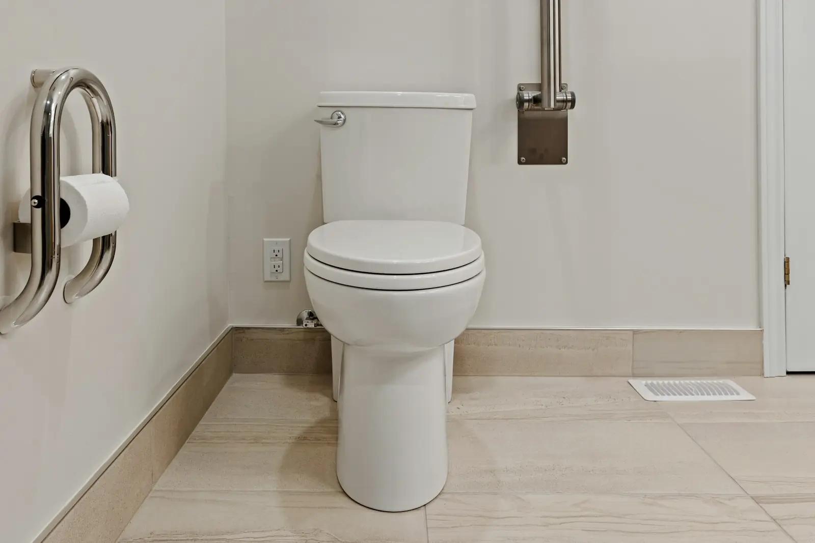 White toilet with a grab rail and toilet roll holder on a tiled floor