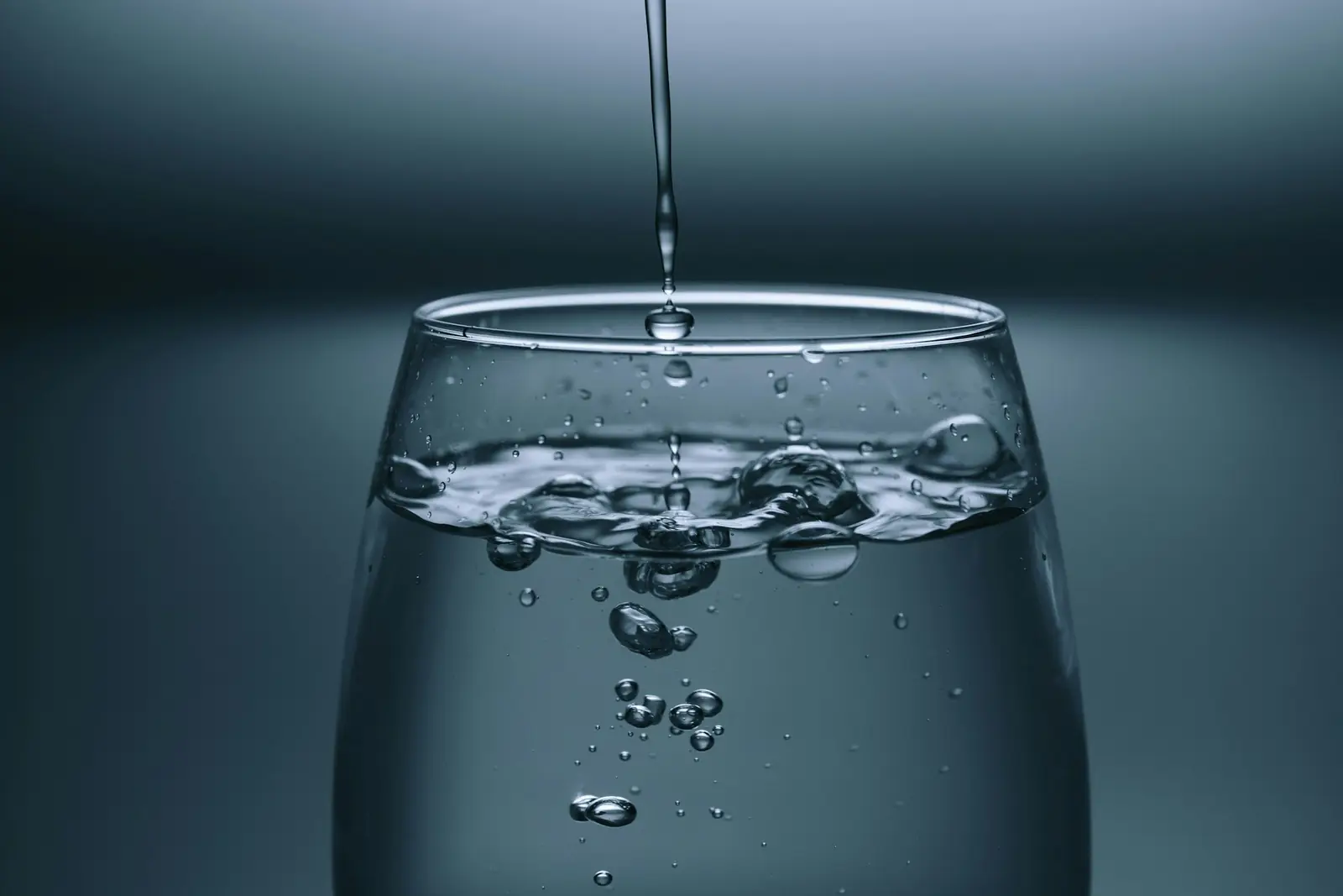 Water pouring into a glass against a dark background