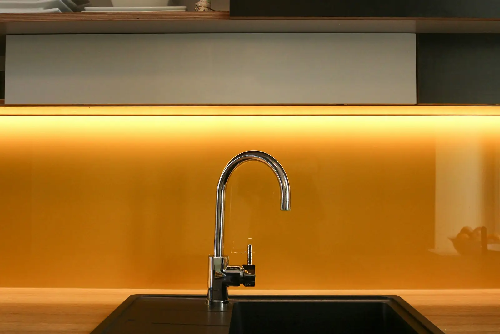 Chrome gooseneck tap over a dark sink with warm lighting