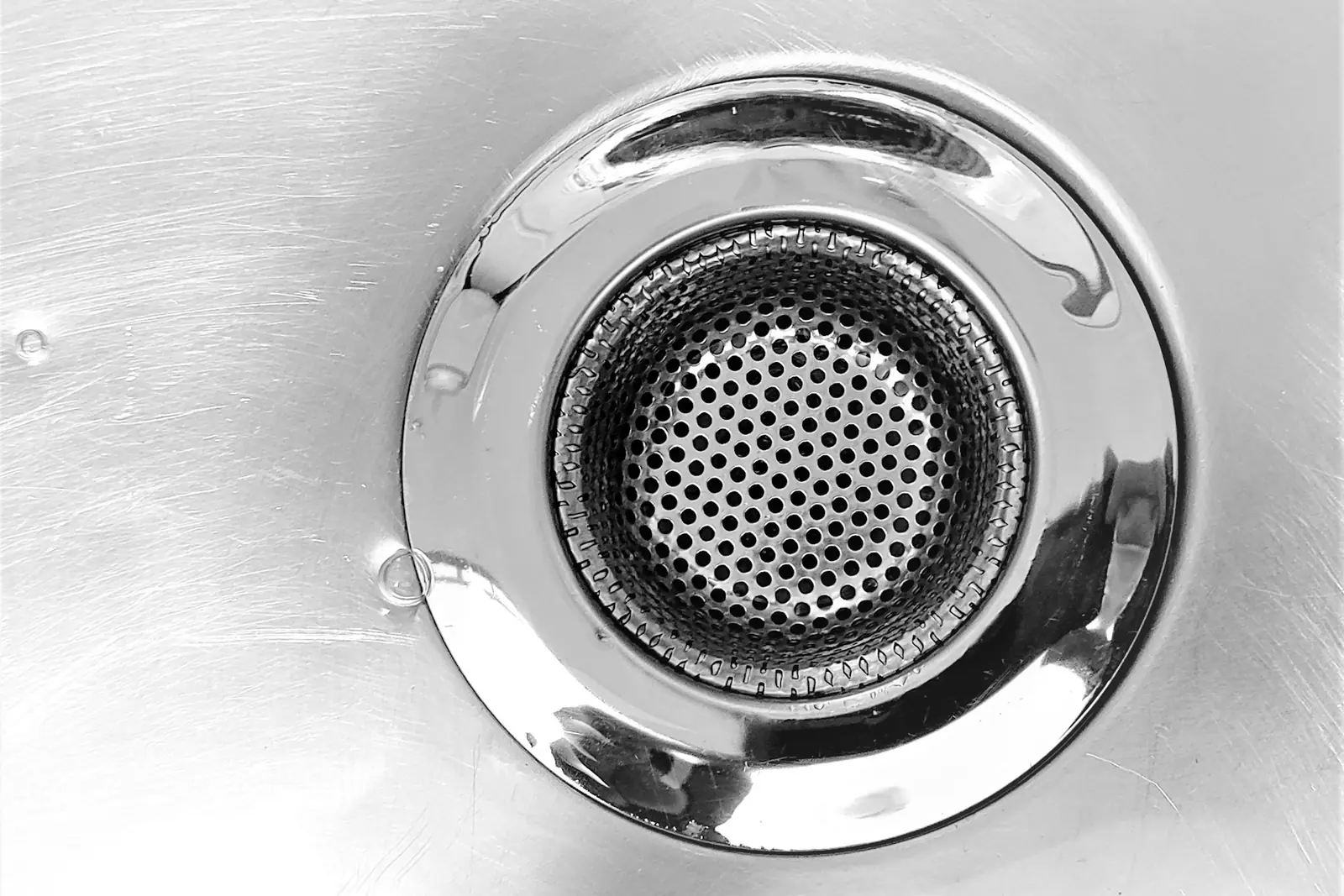 Close-up of a stainless steel sink plughole and strainer
